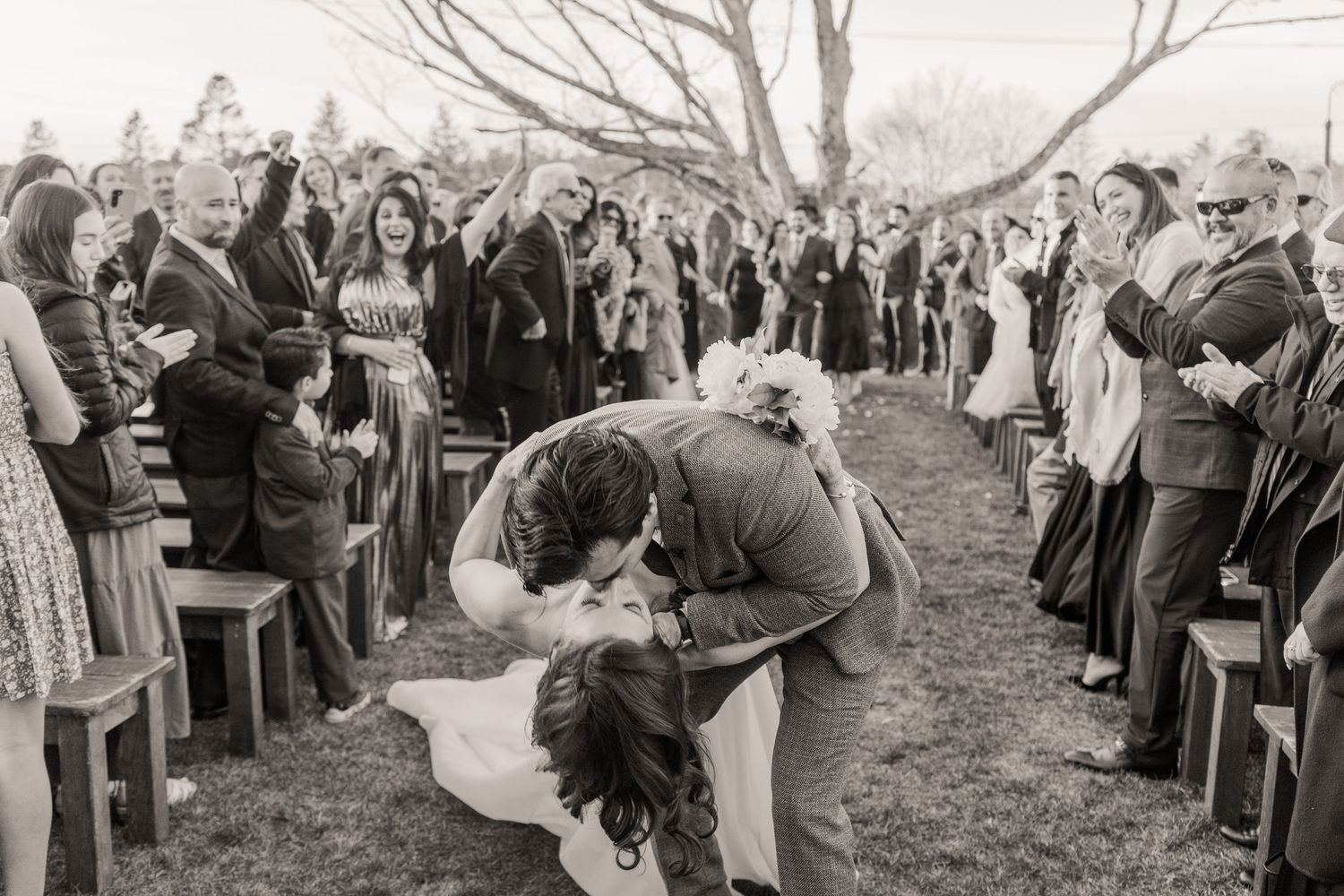 A panoramic view of a crowd gathered outdoors in winter forming two parallel lines during a ceremony.