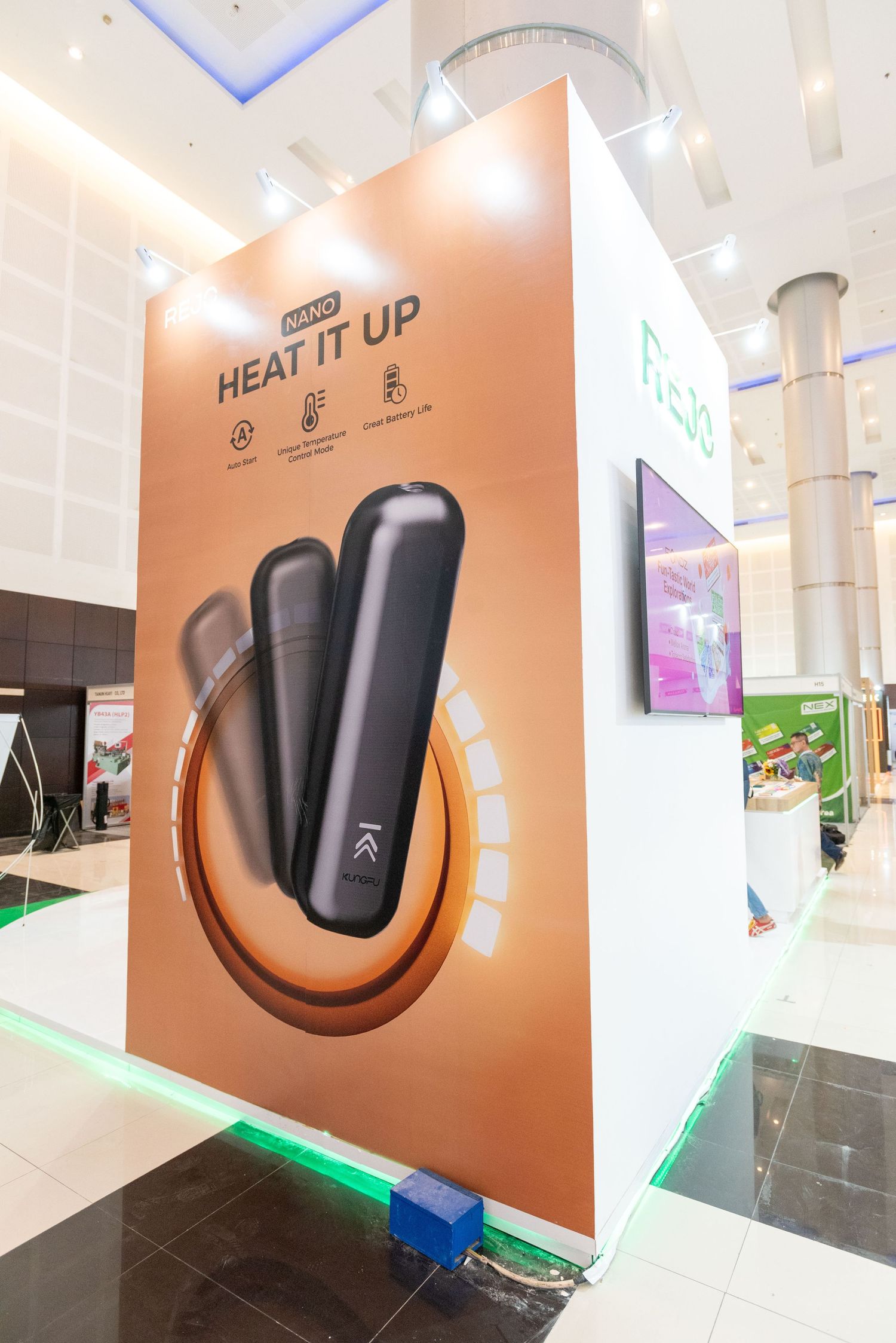 Modern exhibition booth displays sleek black electronic devices mounted on curved copper-colored wall panels with LED lighting.