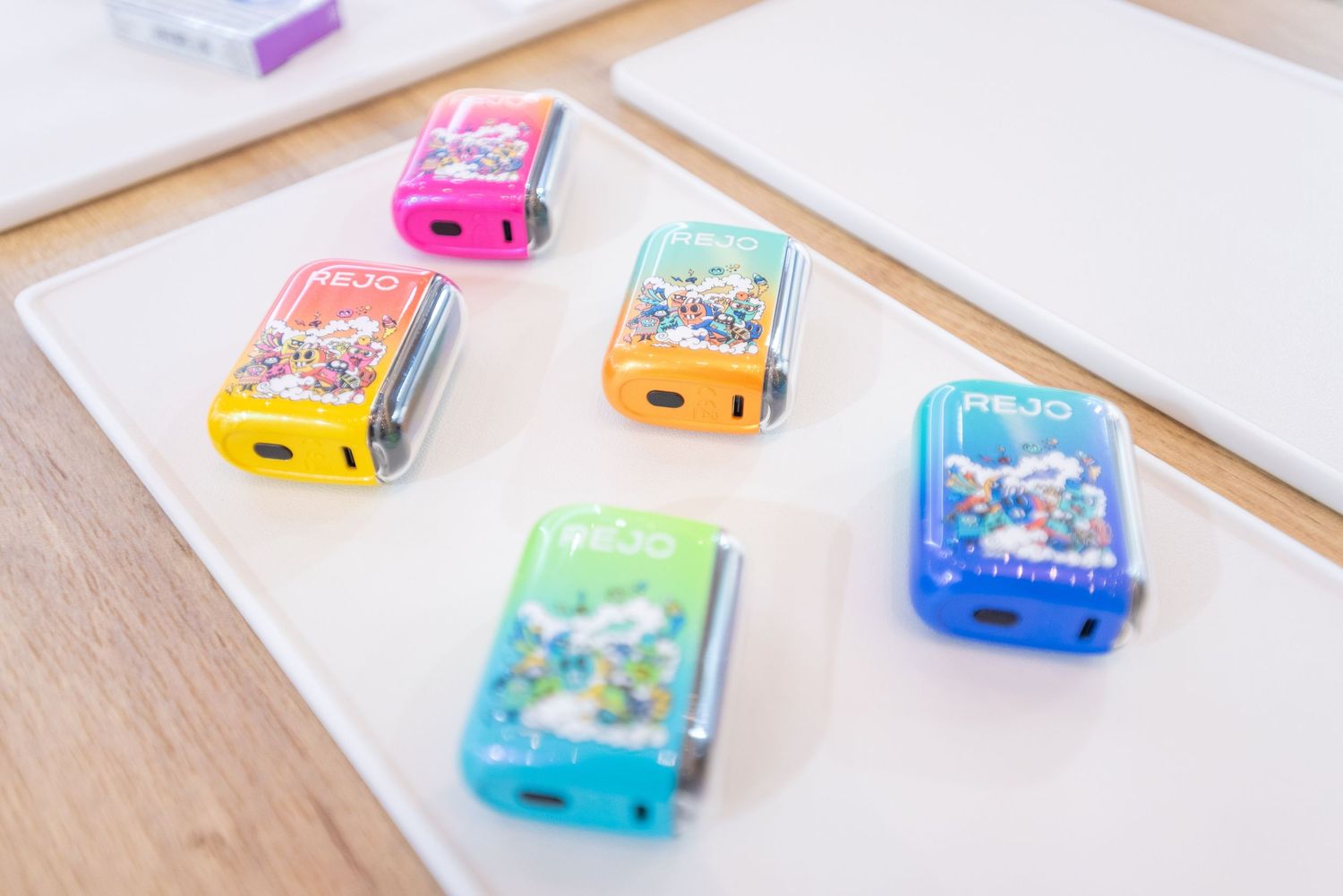Colorful handheld electronic gaming devices arranged in a row on a white surface showing different game screens.