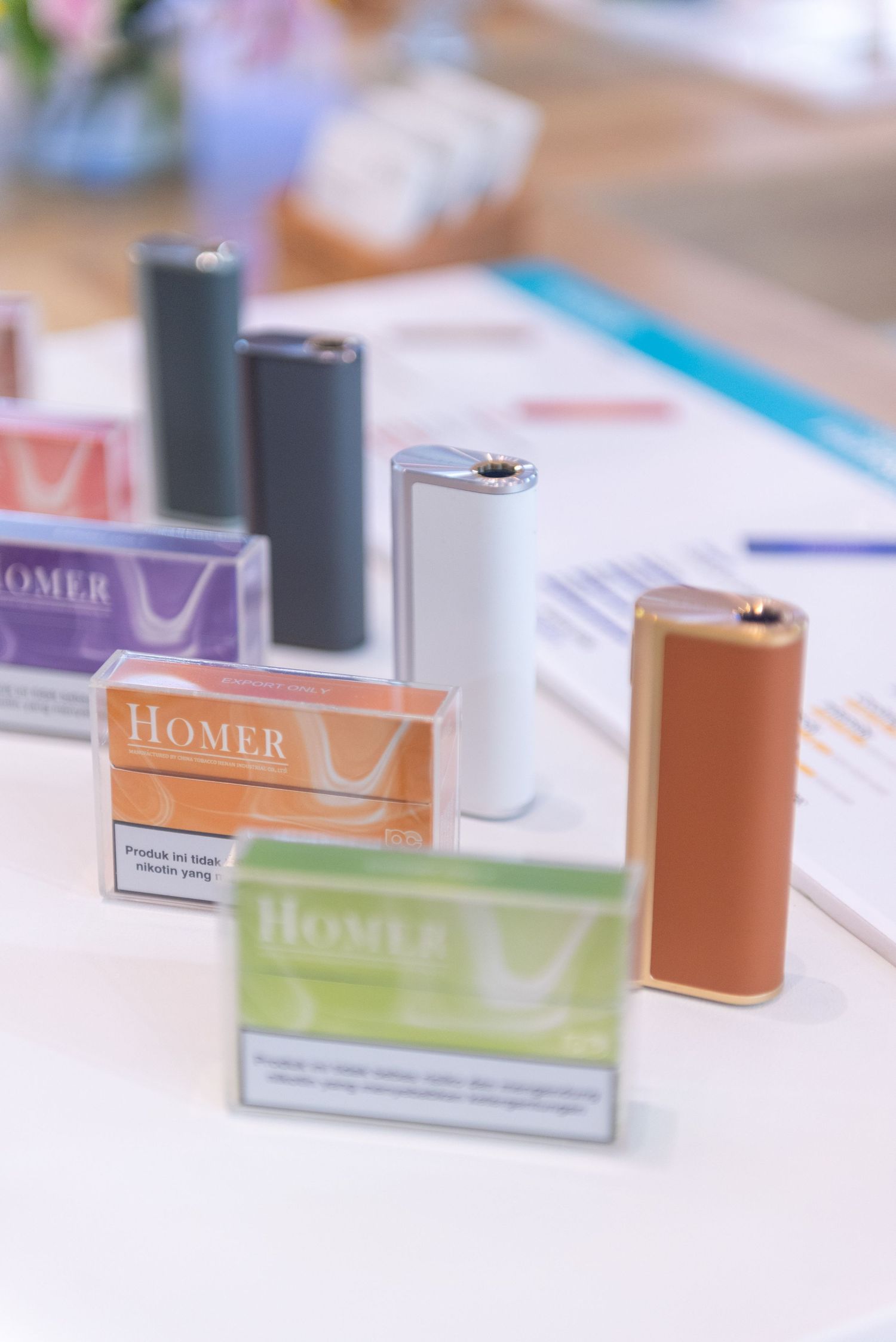 Colorful Homer brand product boxes and batteries arranged on a white surface with soft focus background.