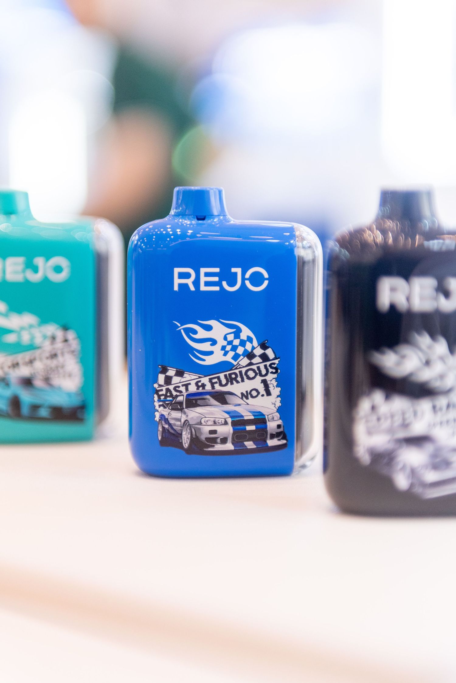 Selective focus shot of blue and black car-themed product containers lined up in a row on a white surface.