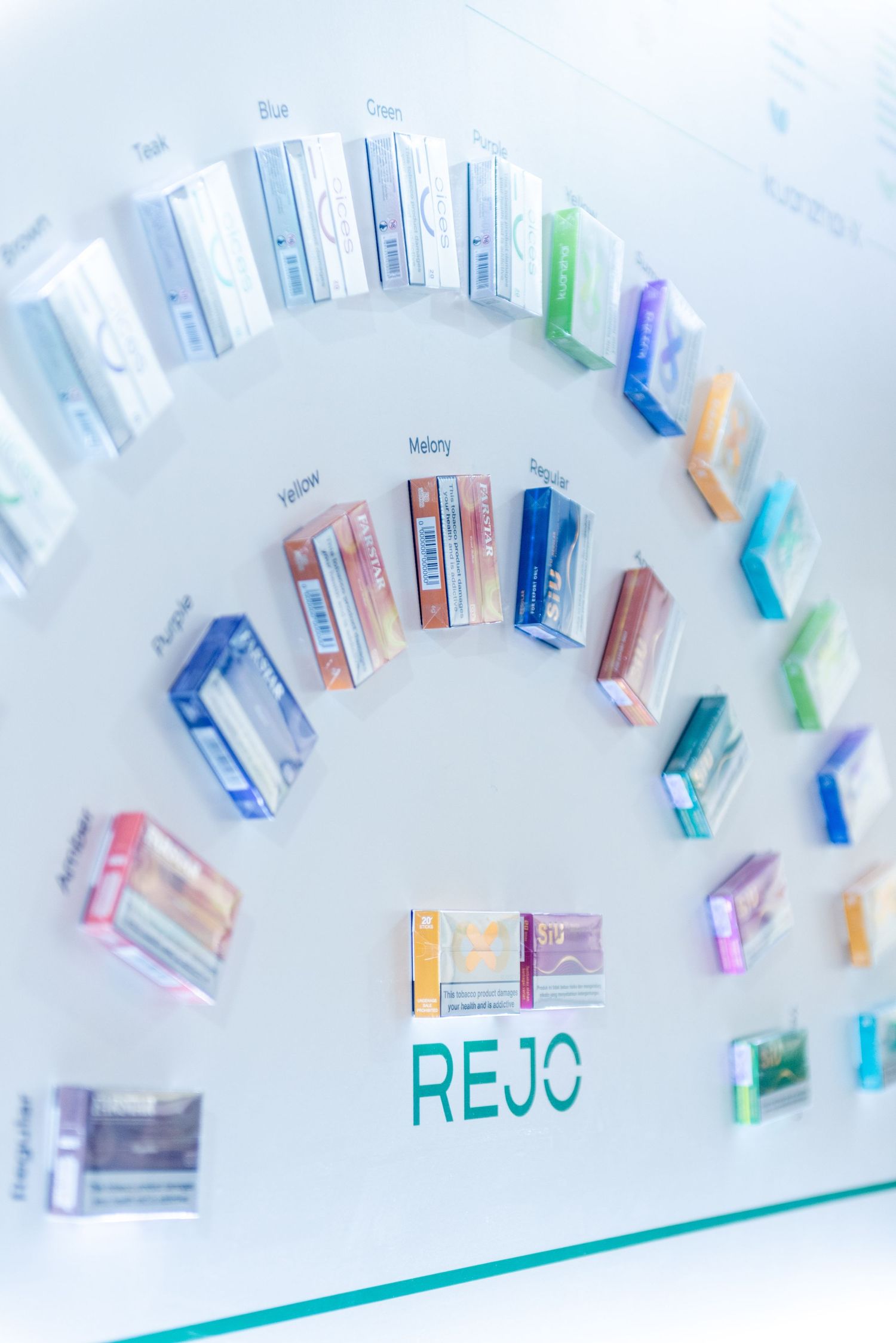 Colorful vape cartridges arranged in a curved pattern on a white surface with blue and green text visible.