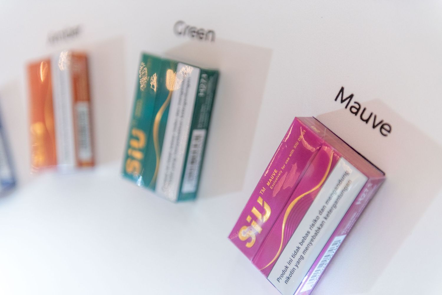 Colorful prescription medicine boxes arranged in a row on a white surface, fading into soft focus at the edges.