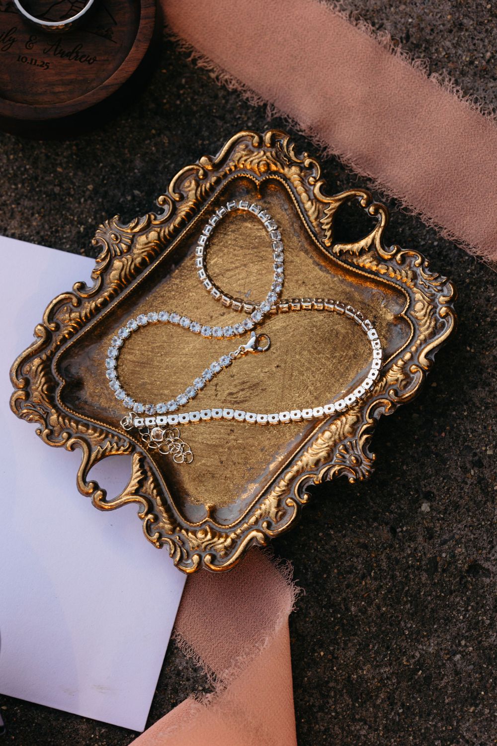 Pearl necklace displayed on an ornate vintage gold frame against a dark background.