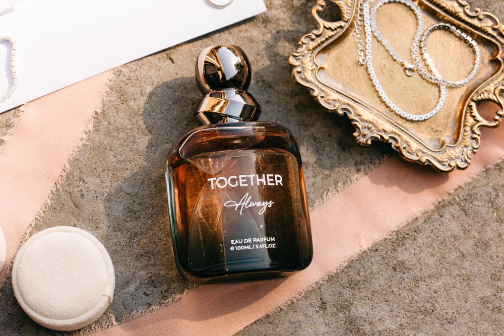Elegant amber perfume bottle labeled 'Together' displayed on pink surface with decorative tray.