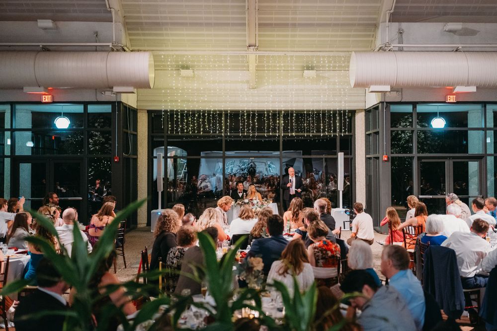 Wedding guests dance in a large group on the dance floor during an evening celebration.