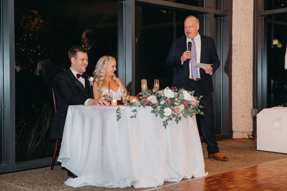 Wedding reception tables decorated with elegant white linens and floral centerpieces in a modern venue.