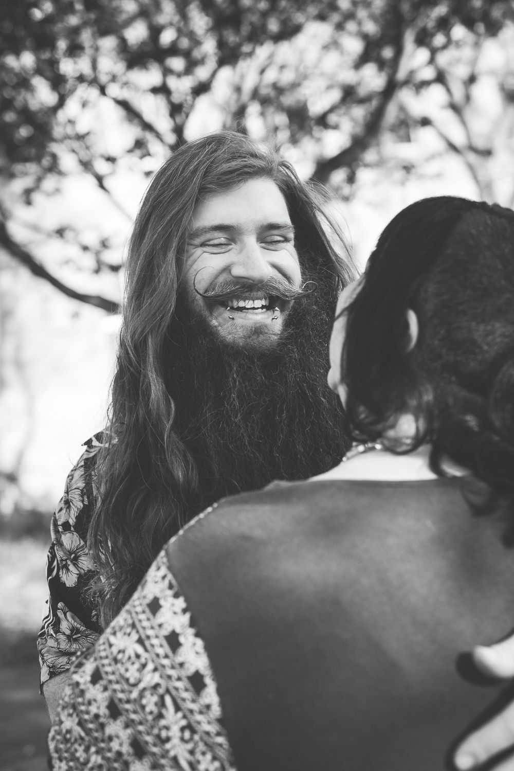 Four sequential black and white photos showing a joyful moment between two people sharing laughter outdoors.