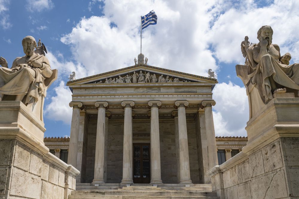 Ancient Greek architecture details showing classical columns and pediments of the Academy of Athens against a blue sky.