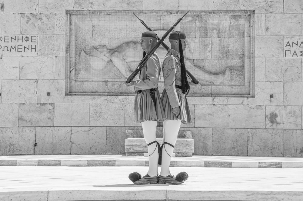 A skateboarder performs a sequence of trick attempts on a concrete ledge in black and white photography.