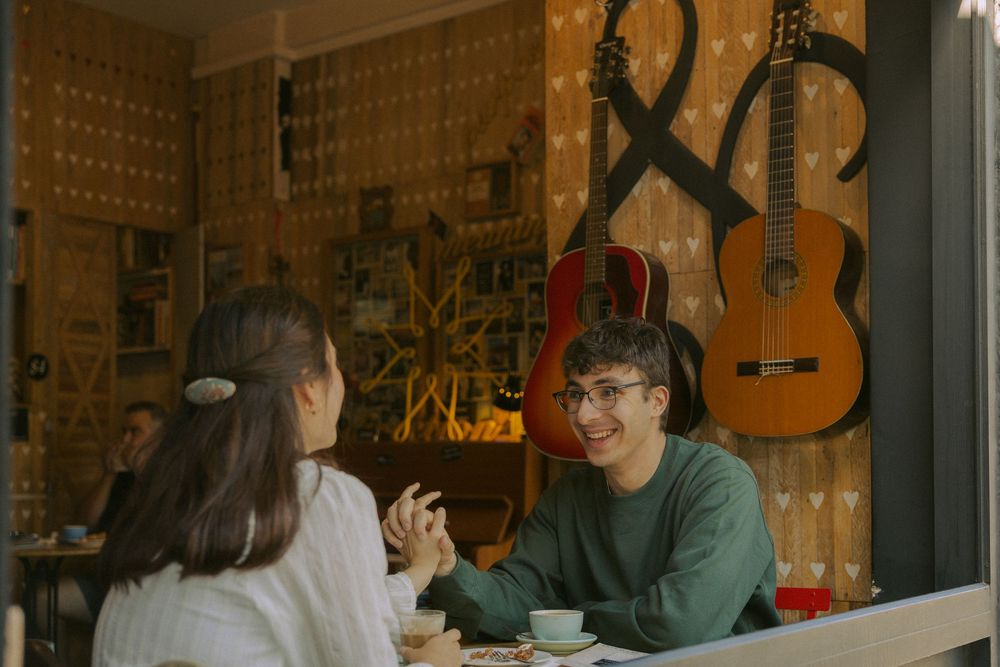 Couple enjoying coffee and conversation in a cozy bookstore cafe with warm lighting and bookshelves.