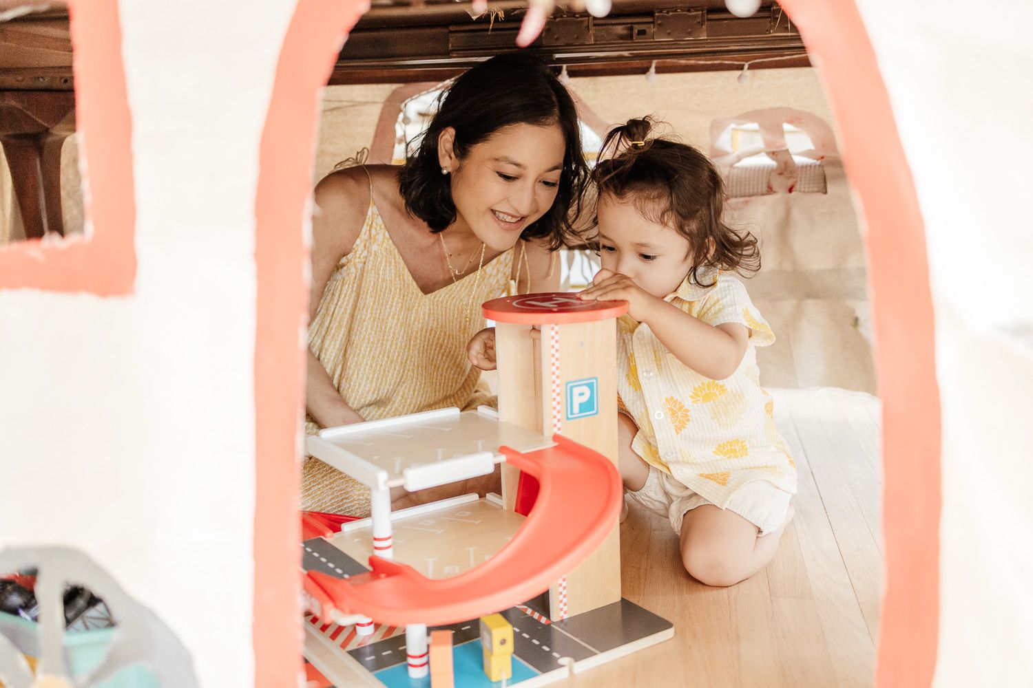 a mom and her toddler spend time in their tent with toys during their in-home newborn photography session