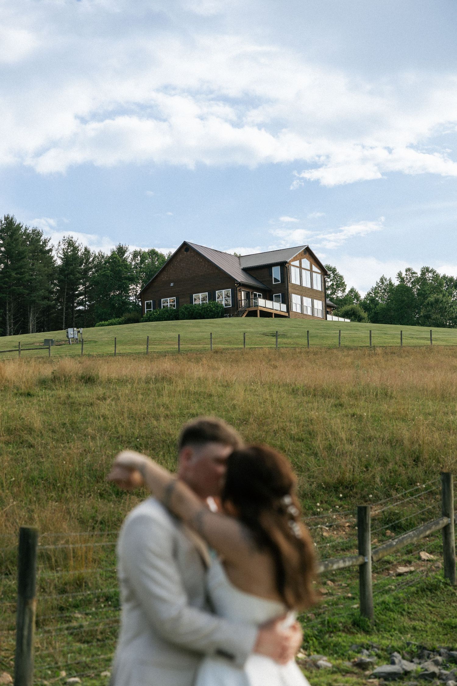 Modern wooden lodges sit atop a scenic grassy hillside under blue summer skies.Micro wedding, elopement, intentional celebration