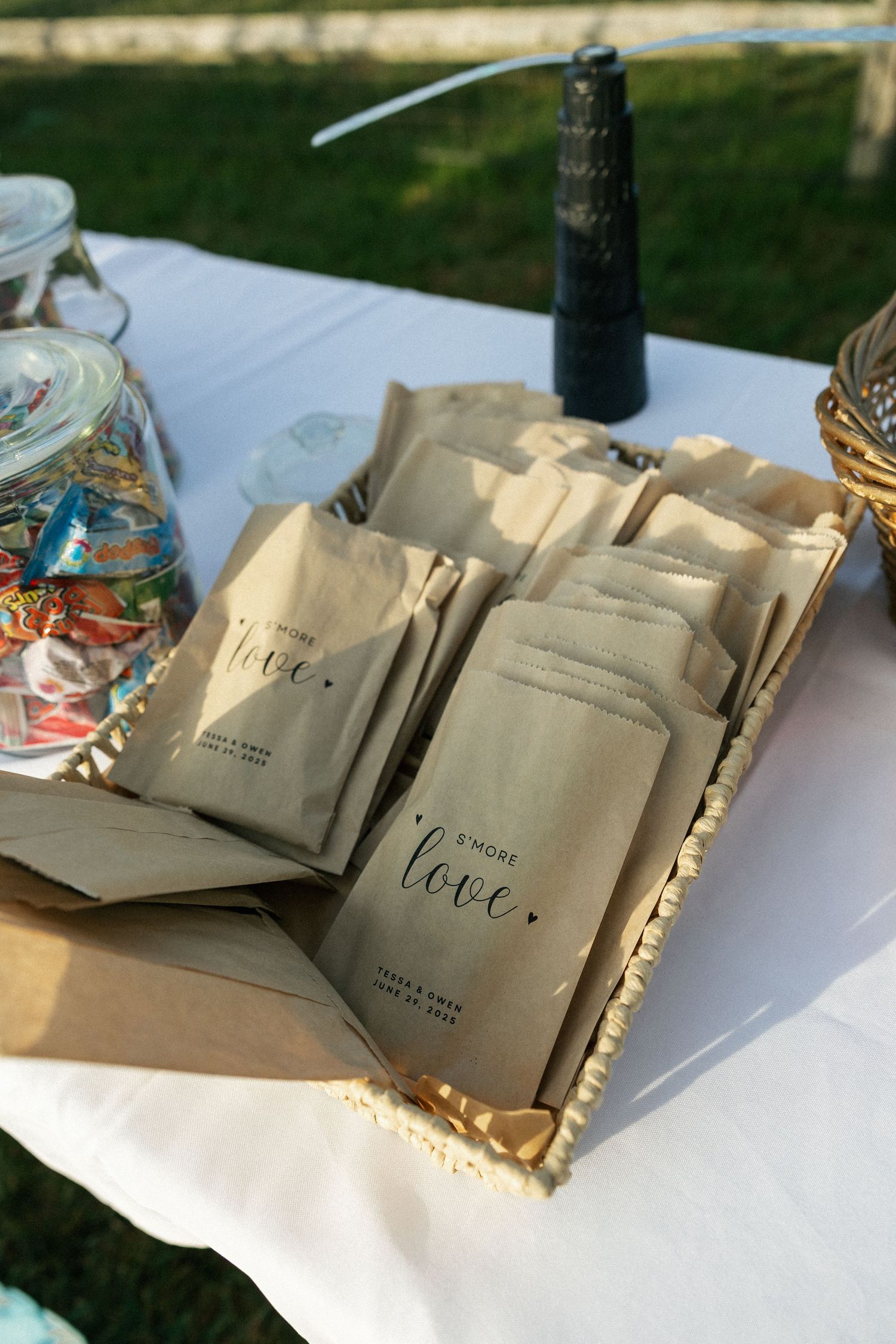 Brown paper gift bags arranged on a white tablecloth at an outdoor event.Micro wedding, elopement, intentional celebration