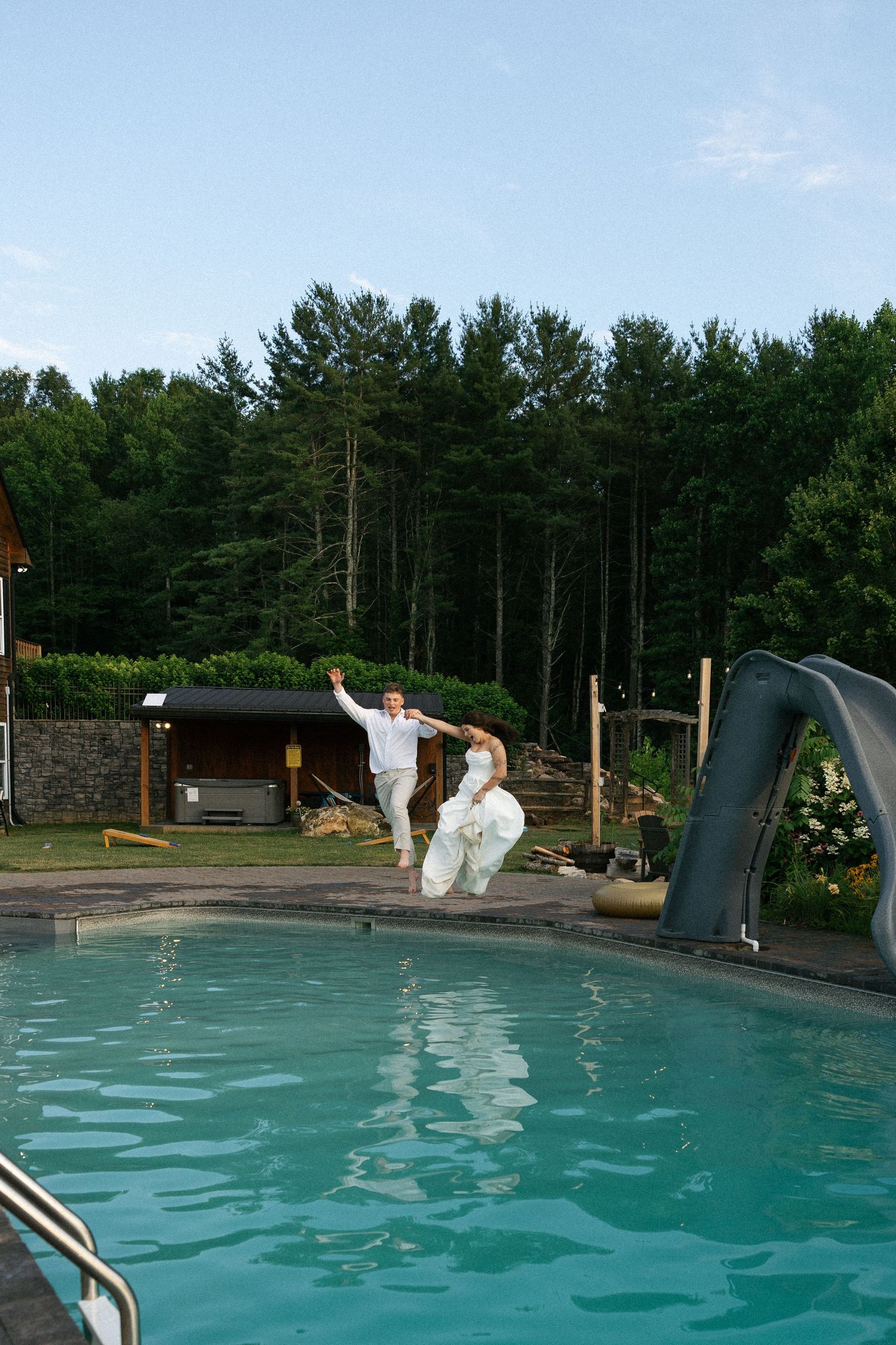 Someone in wedding attire jumps into a swimming pool with a dramatic splash.Micro wedding, elopement, intentional celebration