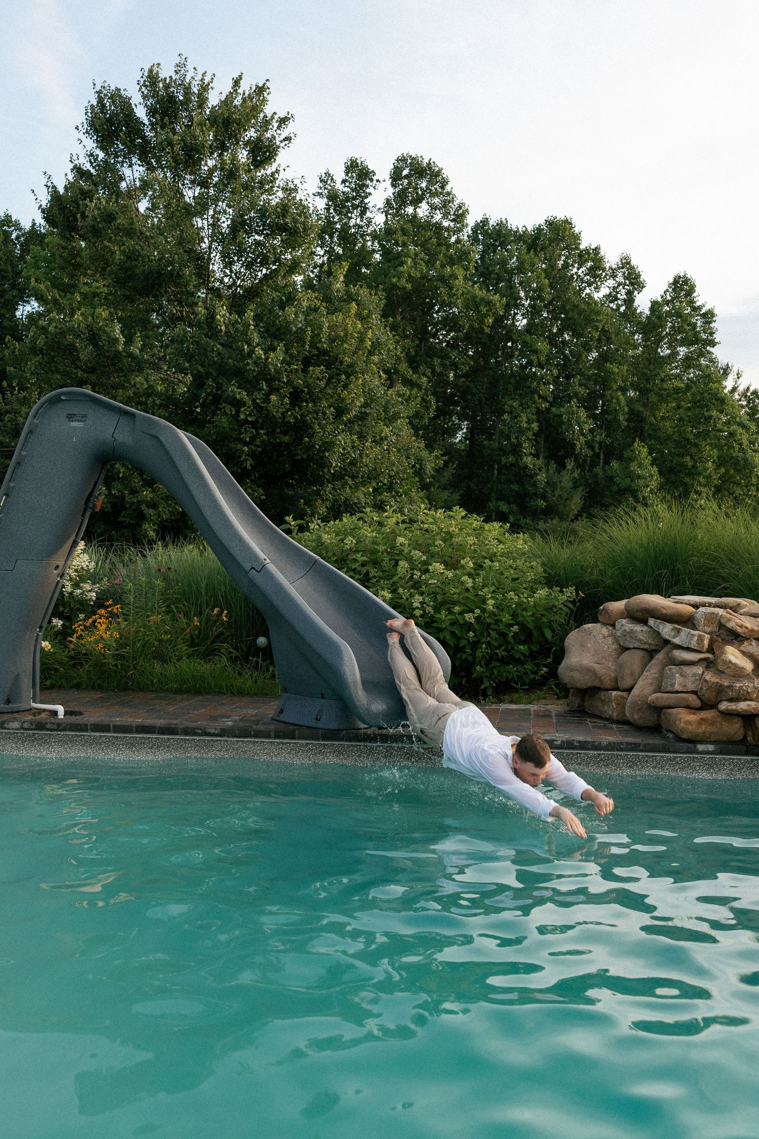 Sequence showing someone diving into turquoise pool water from a waterslide.Micro wedding, elopement, intentional celebration