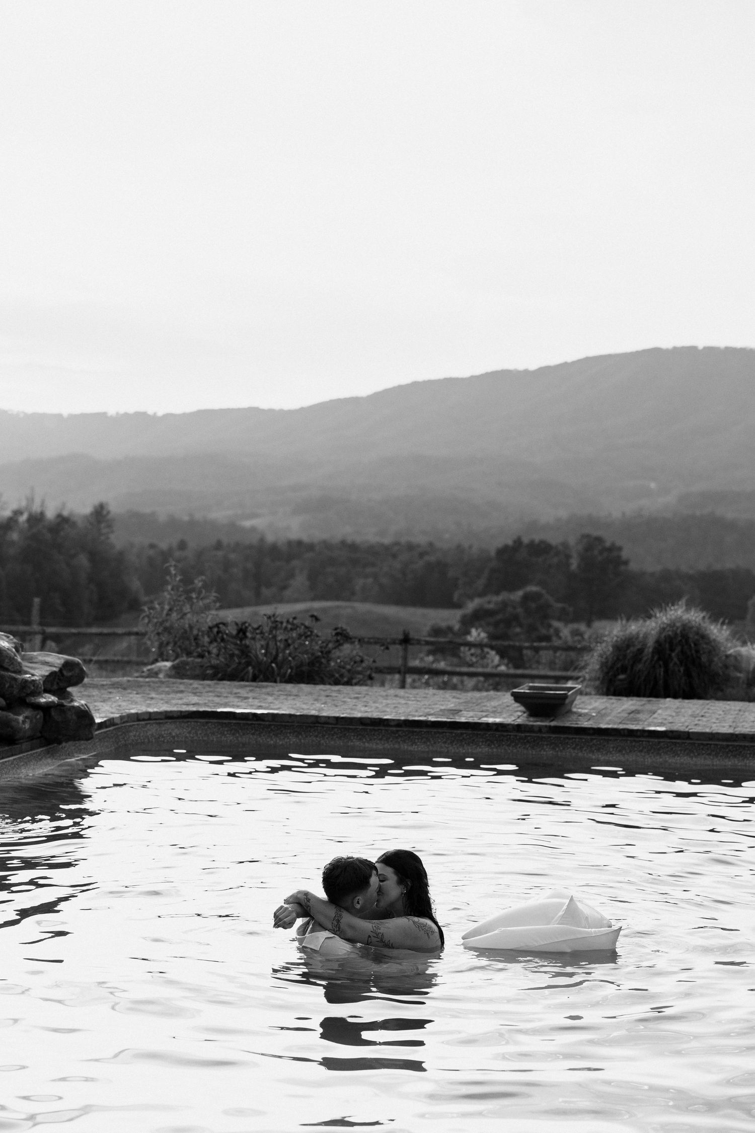 A couple shares an intimate moment while floating in a serene mountain lake at dusk.Micro wedding, elopement, intentional celebration