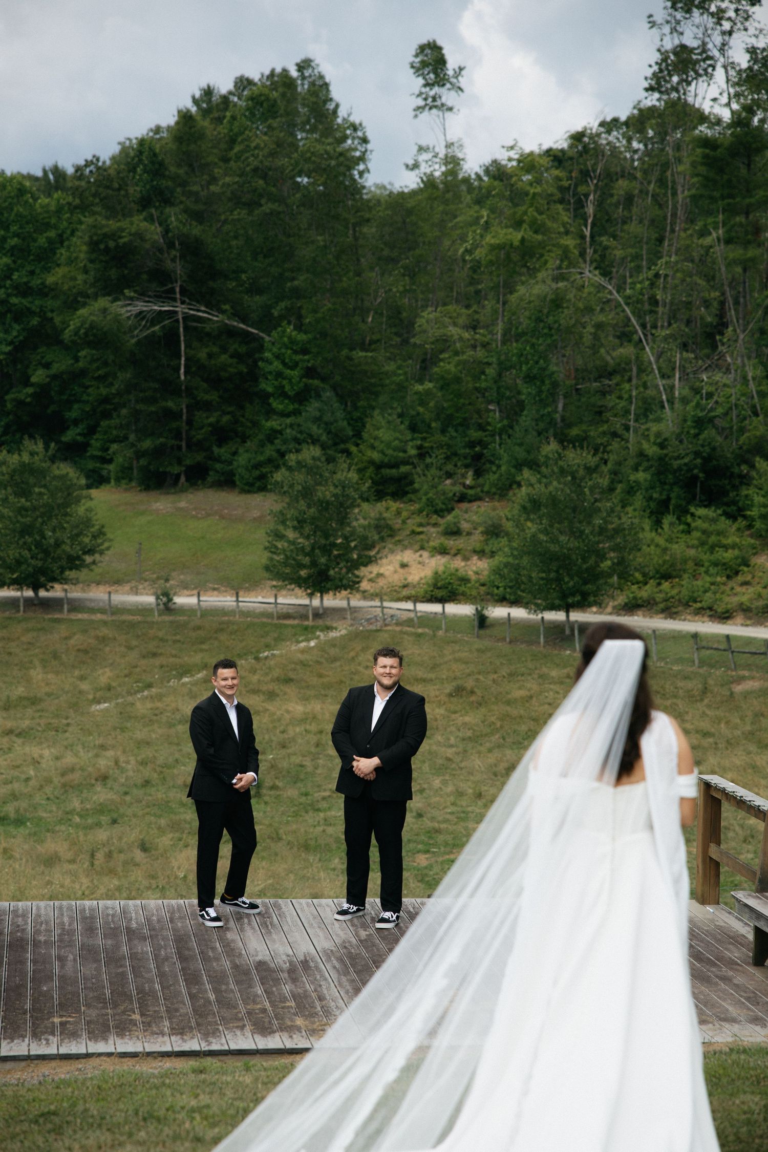 A sequence of wedding photos showing a bride in a white dress sliding down a grassy hill with groomsmen watching.