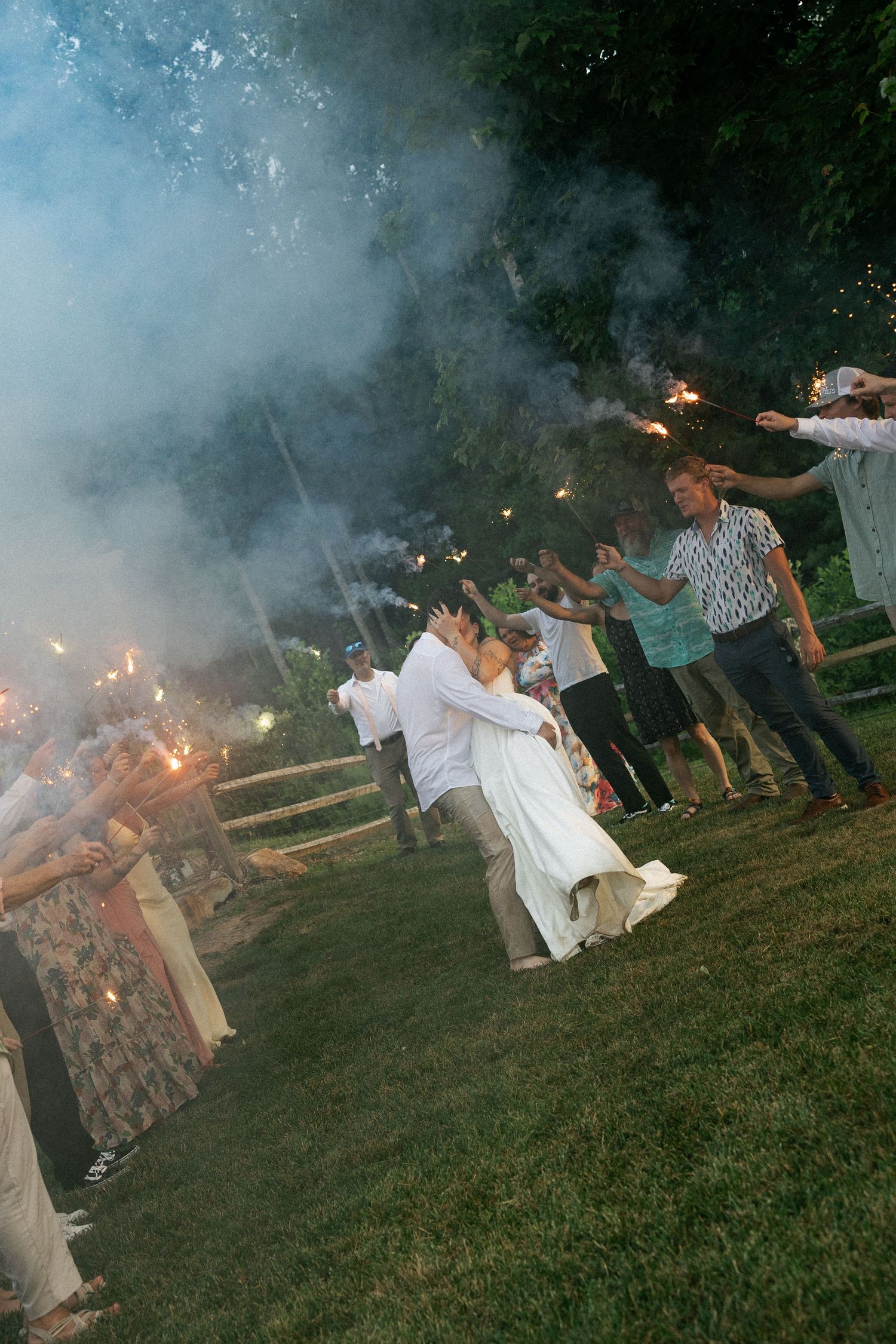 Wedding guests holding sparklers create a magical nighttime send-off tunnel.Micro wedding, elopement, intentional celebration