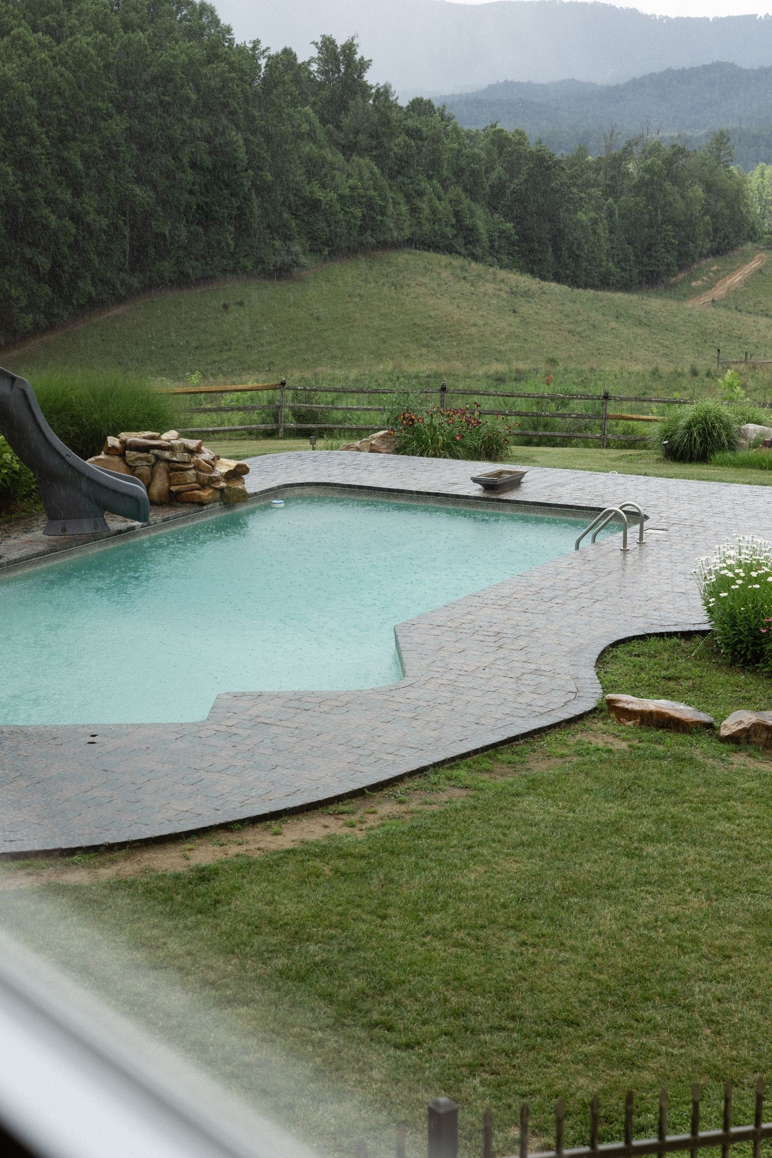 An infinity pool overlooking mountain views with stone patio and lush landscaping at a luxury venue. Micro wedding, elopement, intentional c
