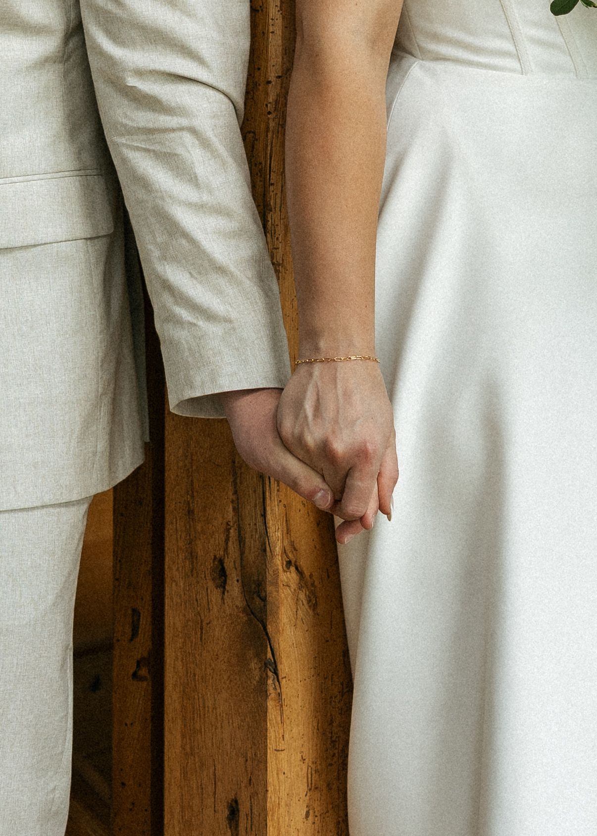 Close-up shot of hands in formal attire against a rustic wooden wall background.Micro wedding, elopement, intentional celebration