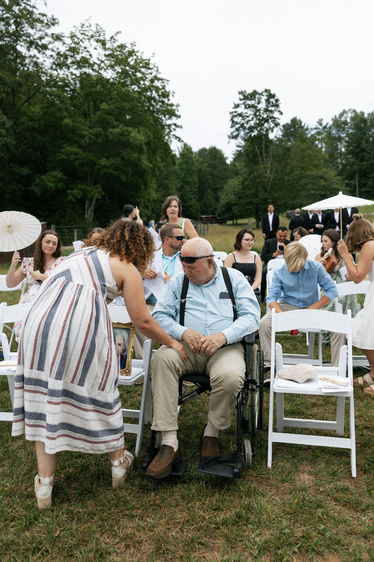 White folding chairs arranged on grass for an outdoor wedding ceremony.Micro wedding, elopement, intentional celebration