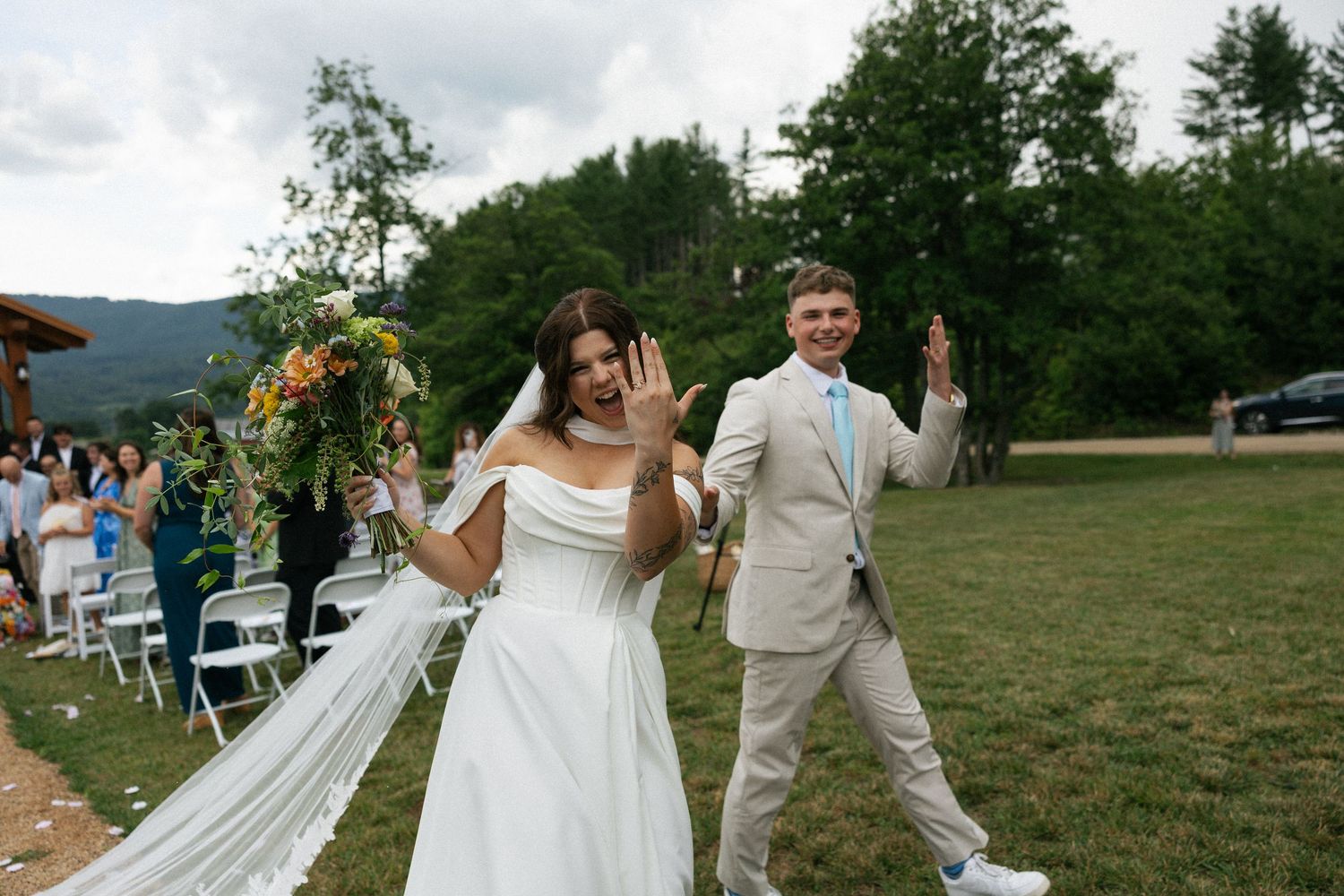 Wedding couple walking together on a grassy field with mountains in the background.Micro wedding, elopement, intentional celebration