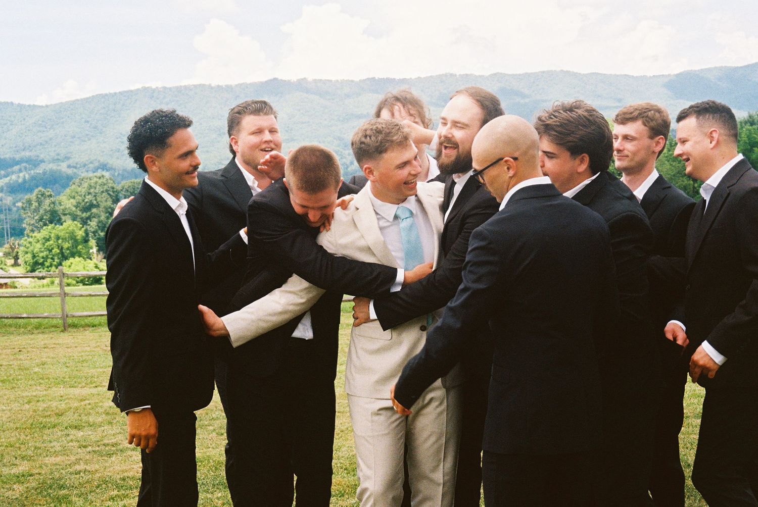 Groomsmen in black suits share a lighthearted moment together on a scenic mountain overlook.Micro wedding, elopement, intentional celebratio