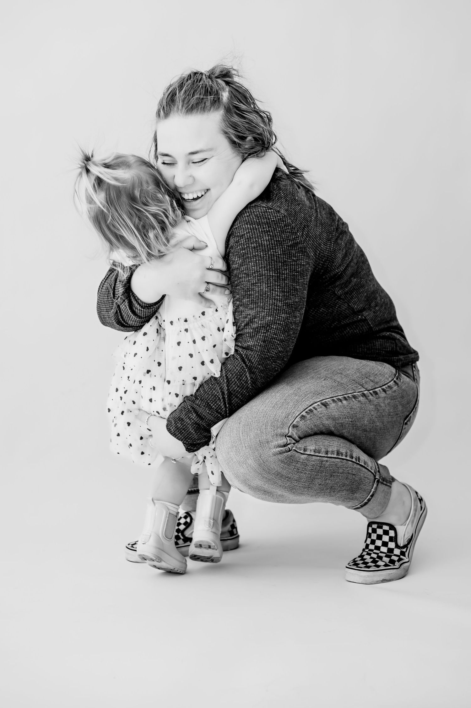 Black and white artistic photo sequence showing a person in polka dot top and jeans crouching down in four poses.