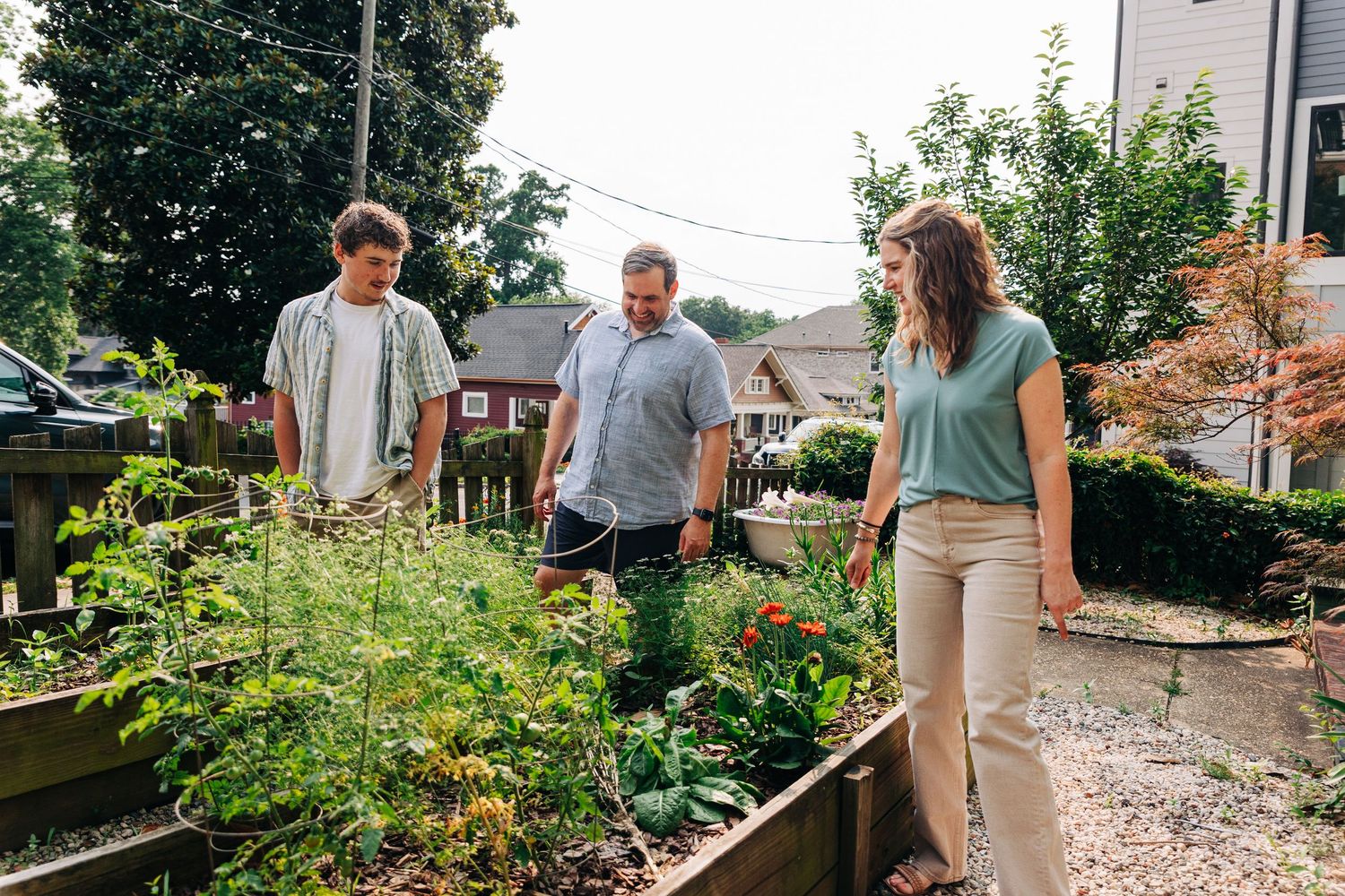 Family spending time together in around their garden with raised beds and gravel pathways on a sunny day in Charlotte, NC.