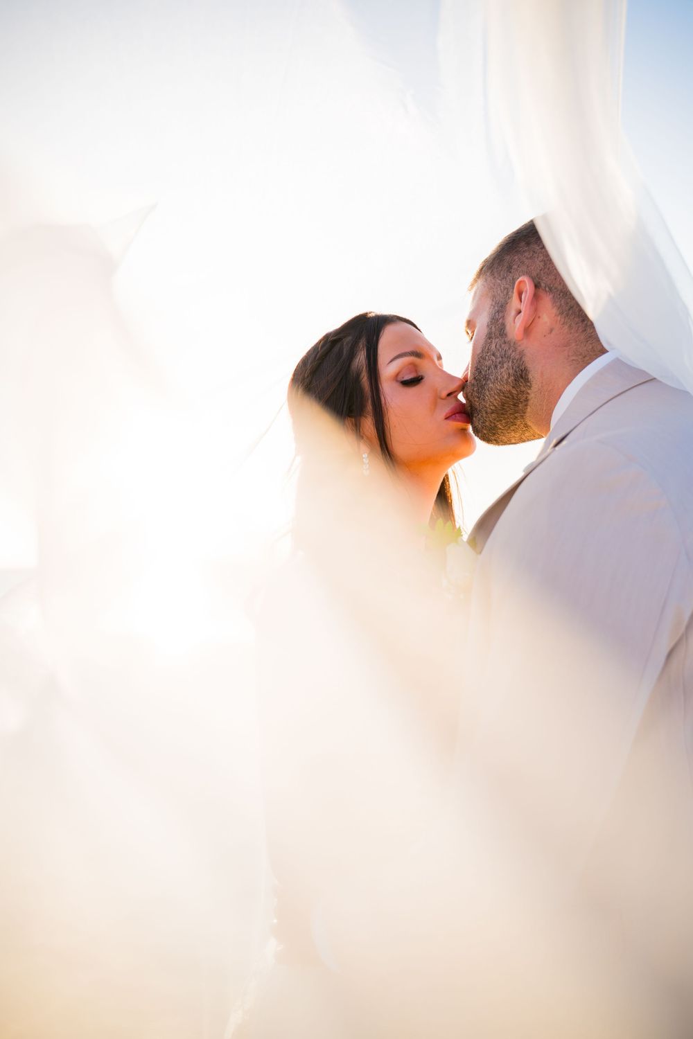 Ethereal wedding photography with soft white veil creating dreamy light effects.