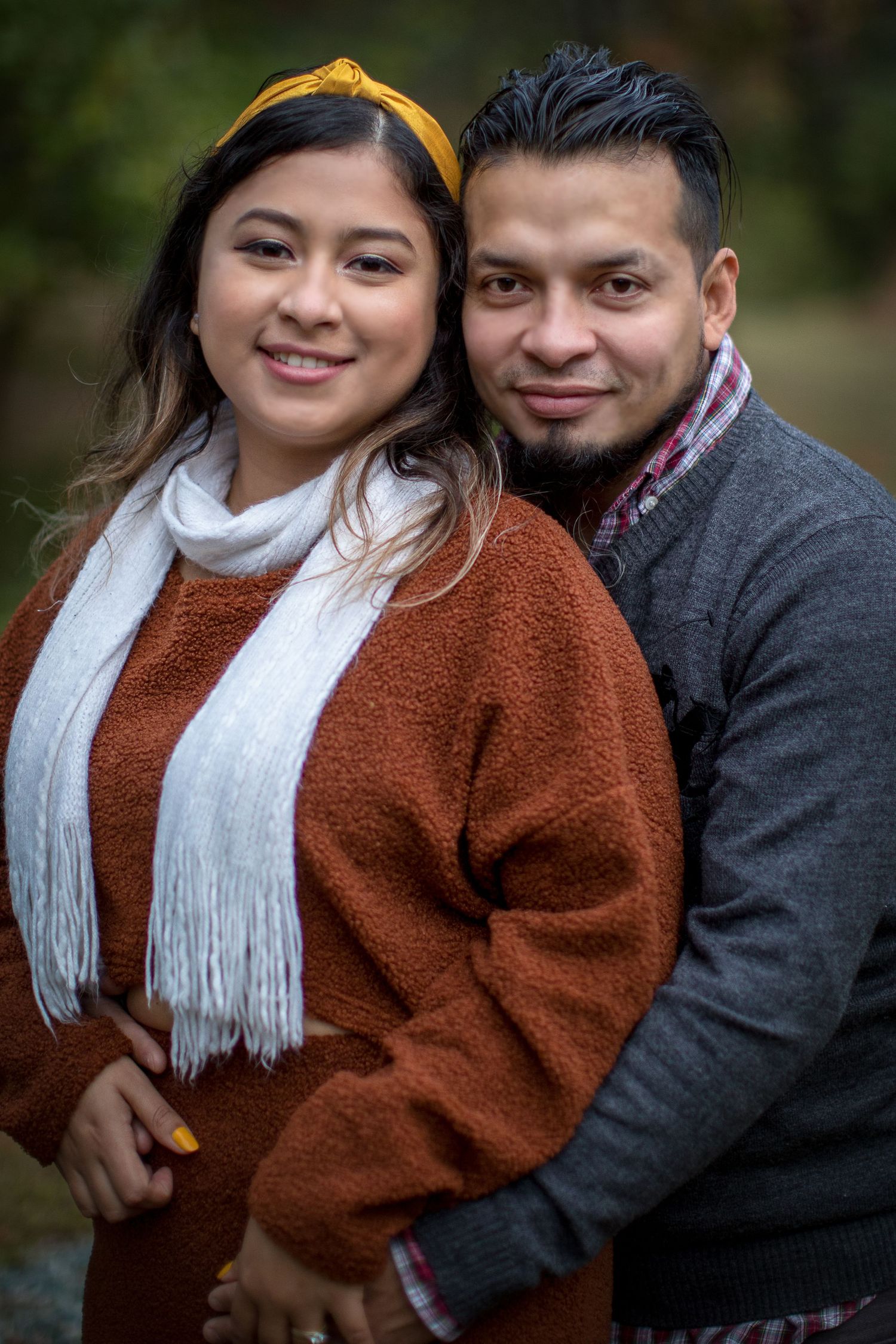A couple in winter attire share intimate moments outdoors, with the person wearing a brown sweater and white scarf.