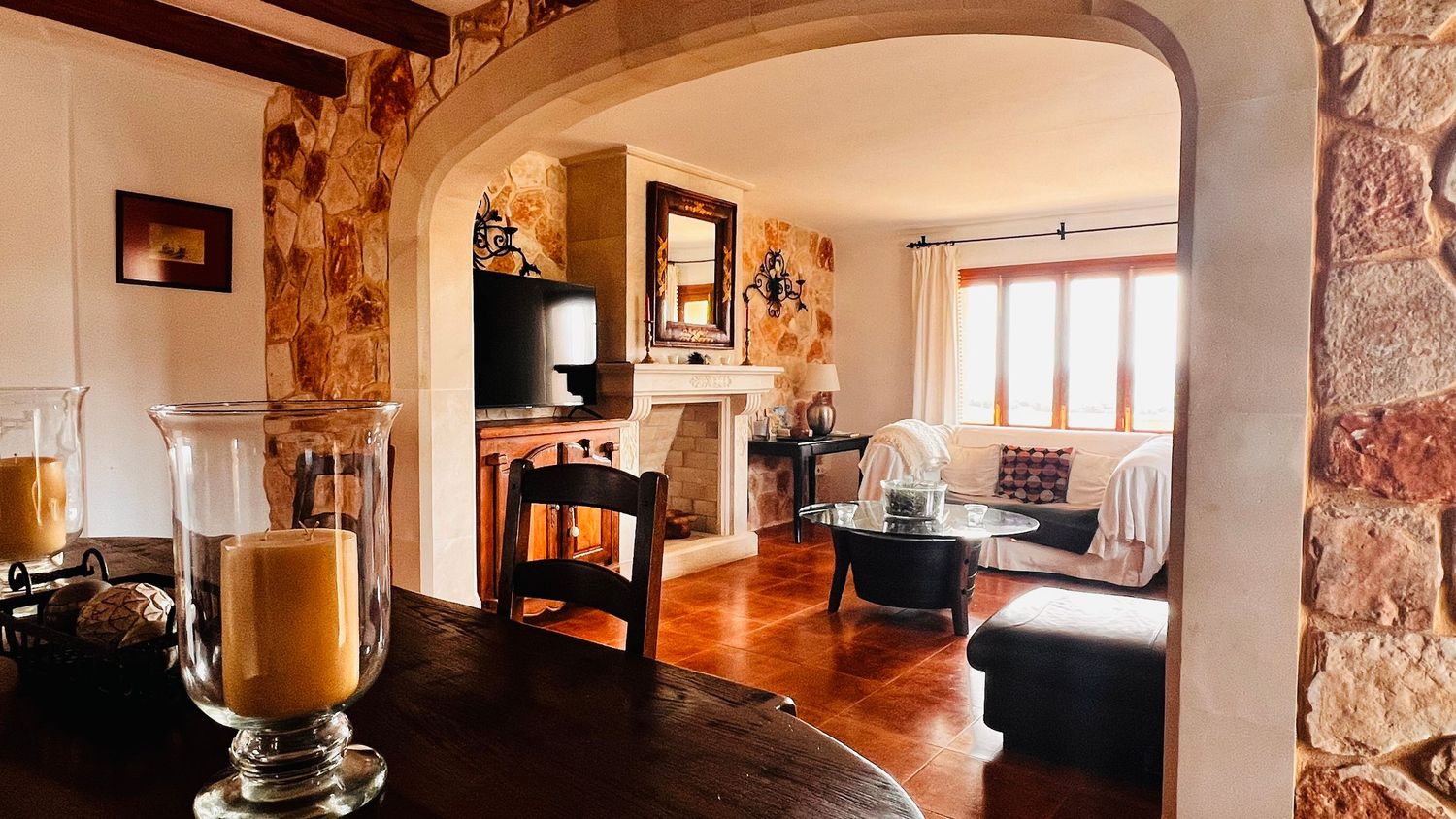 Rustic stone archway leading to elegant living room with fireplace, hardwood floors, and cozy seating area.