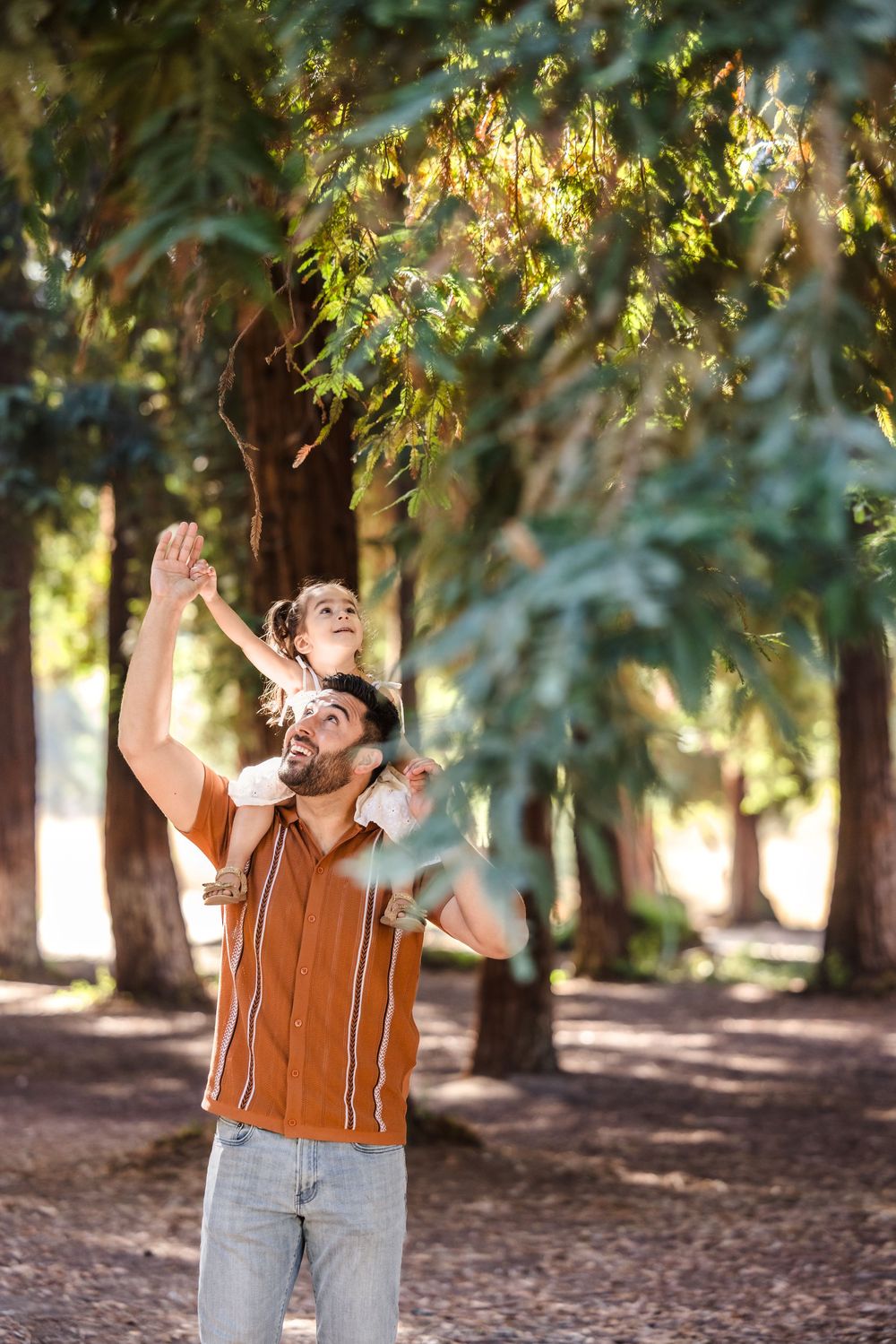 A joyful moment captured beneath sunlit trees in a park on a warm afternoon.