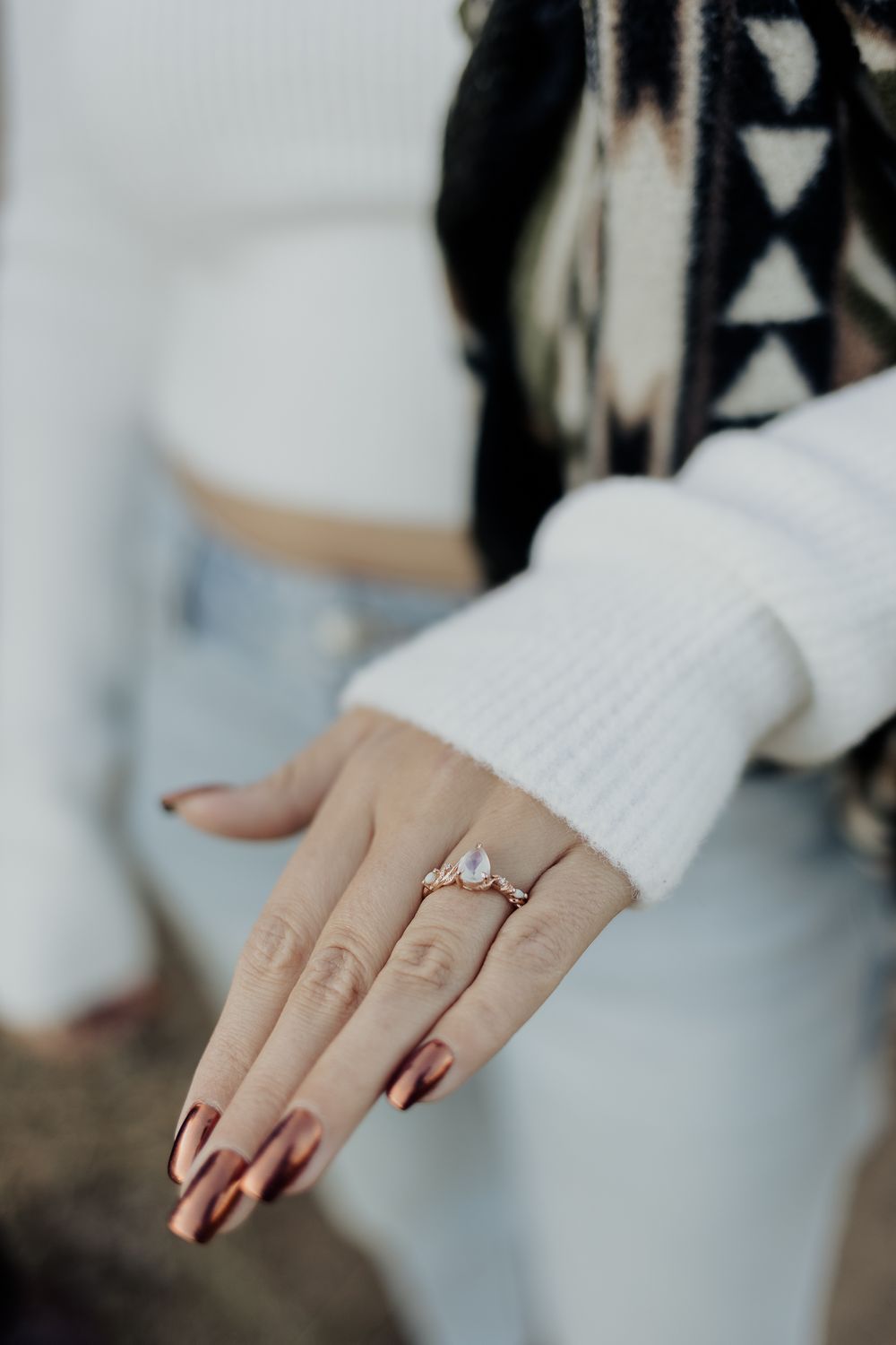 Close-up sequence of a hand wearing a white knit sleeve and displaying an engagement ring with crystal gem detailing.