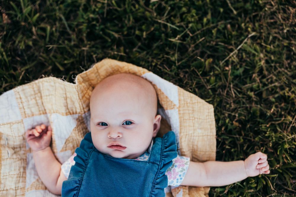 A set of images showing a baby in different poses and expressions outdoors in nature settings.