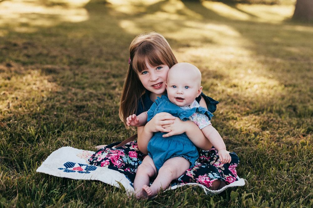 Seven photos show connected moments between siblings sitting together on a blanket outdoors during golden hour.