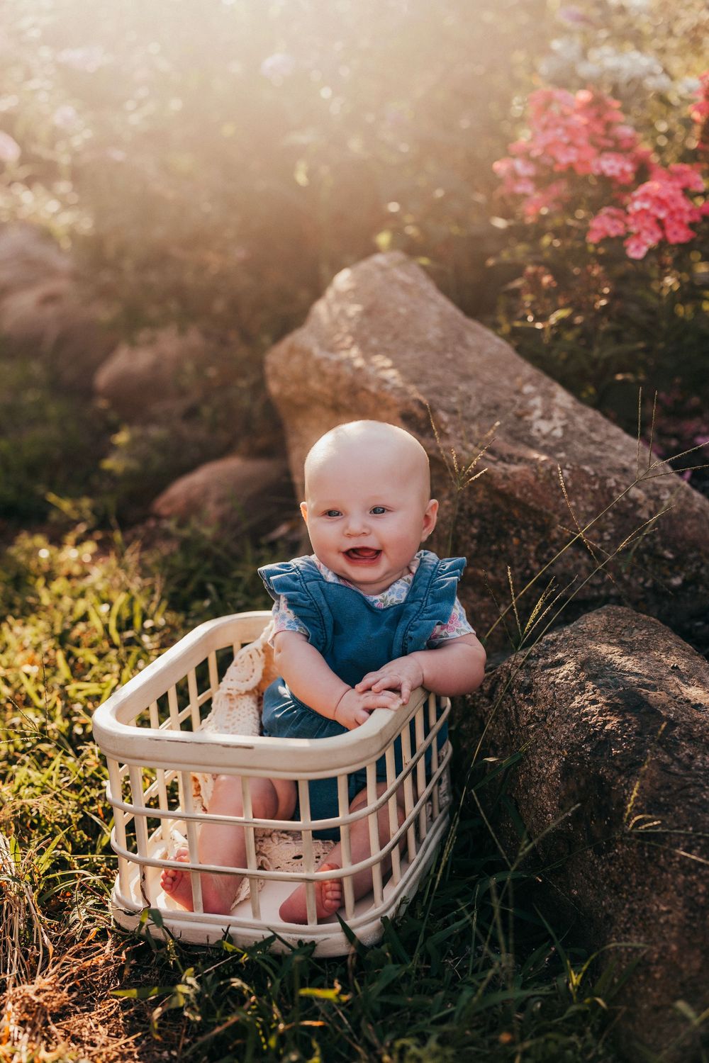 A series of candid photos showing a baby sitting in a white laundry basket outdoors amid flowers and natural sunlight.