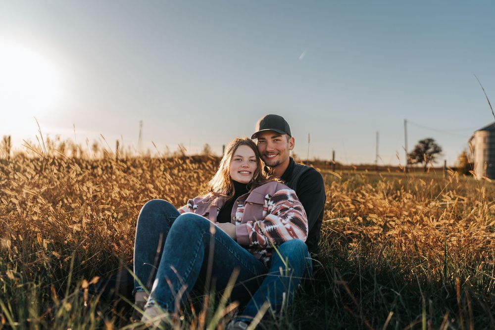 Couple sitting together in a cornfield during golden hour.