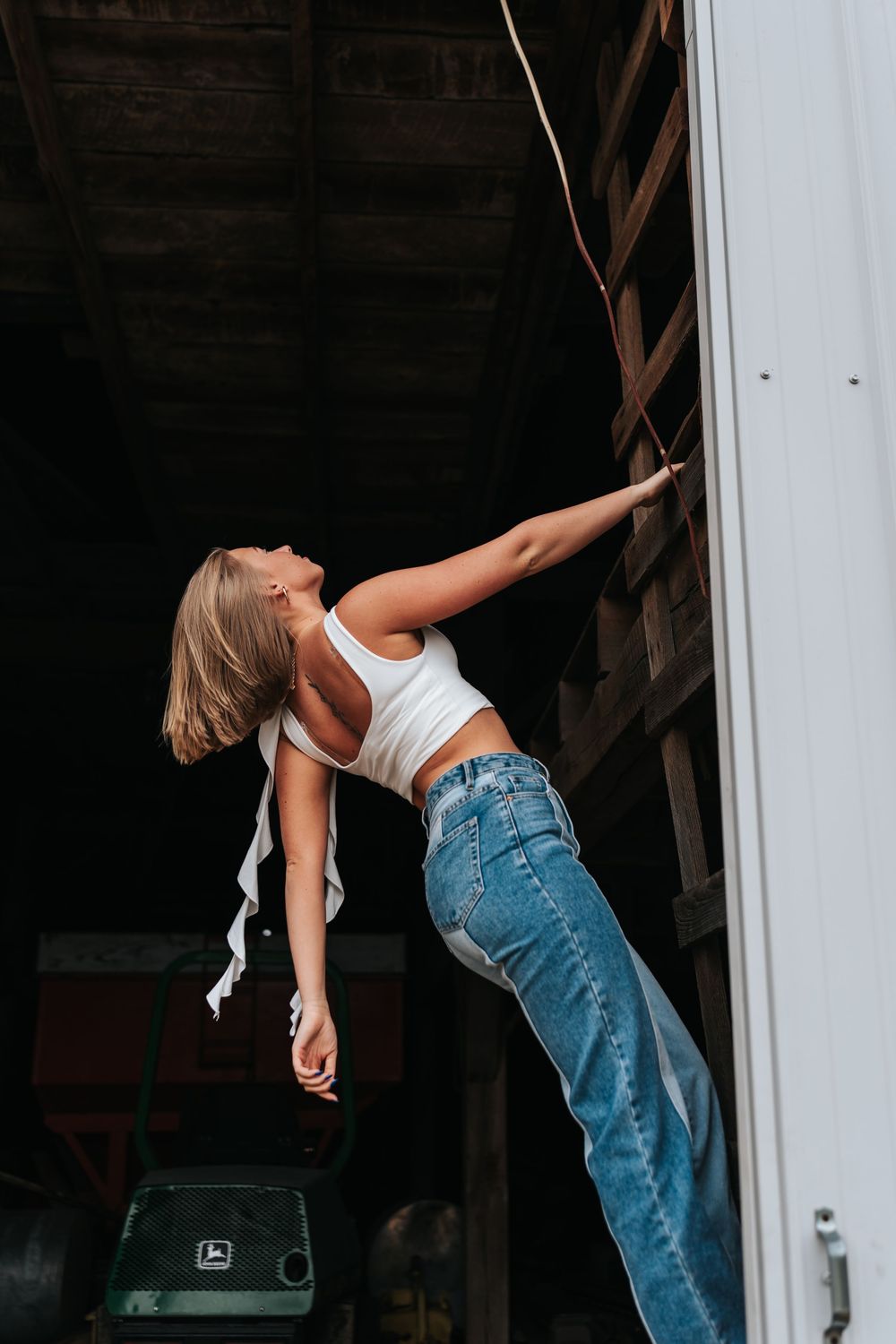 Person in denim jeans performing dance moves against a white wall.