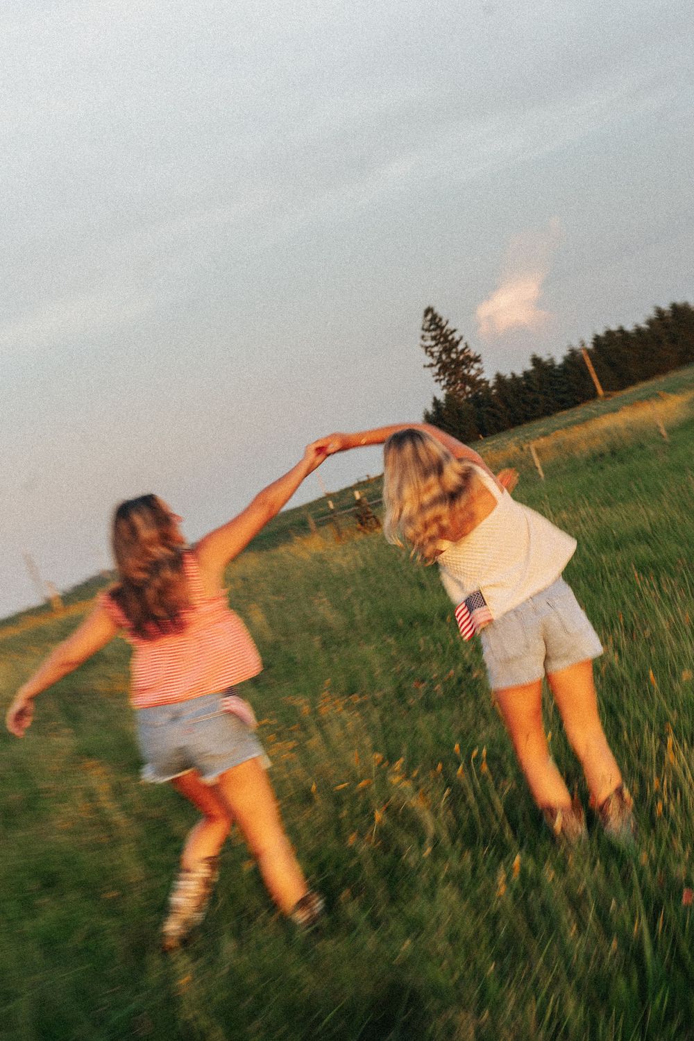 Dynamic motion shots of people dancing and twirling in a grassy field at sunset.