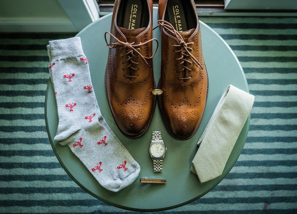 Brown leather dress shoes and floral socks arranged on a striped surface.
