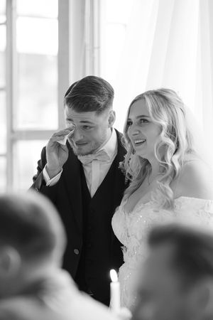 Wedding party members share genuine laughter during indoor reception celebration.