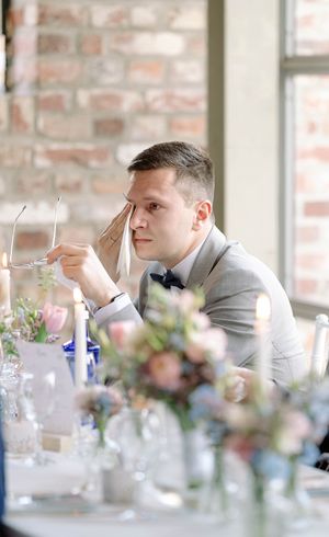 Wedding reception table decorated with floral arrangements and glassware in bright indoor setting.