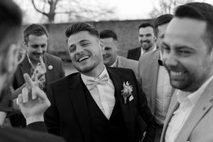 Black and white candid photo of people laughing and socializing at a formal event.