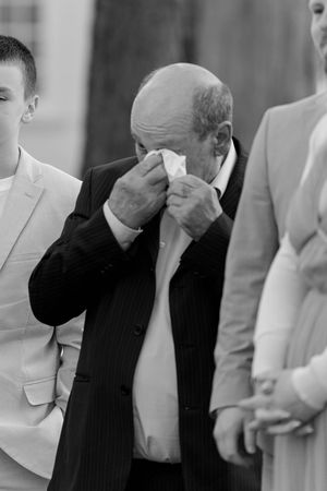 An emotional guest wipes tears during a touching wedding ceremony moment.