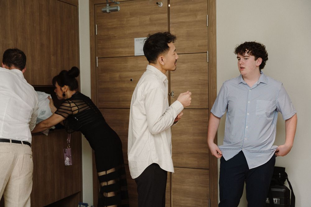 Interior hallway scene showing casual interactions between people in light colored clothing.