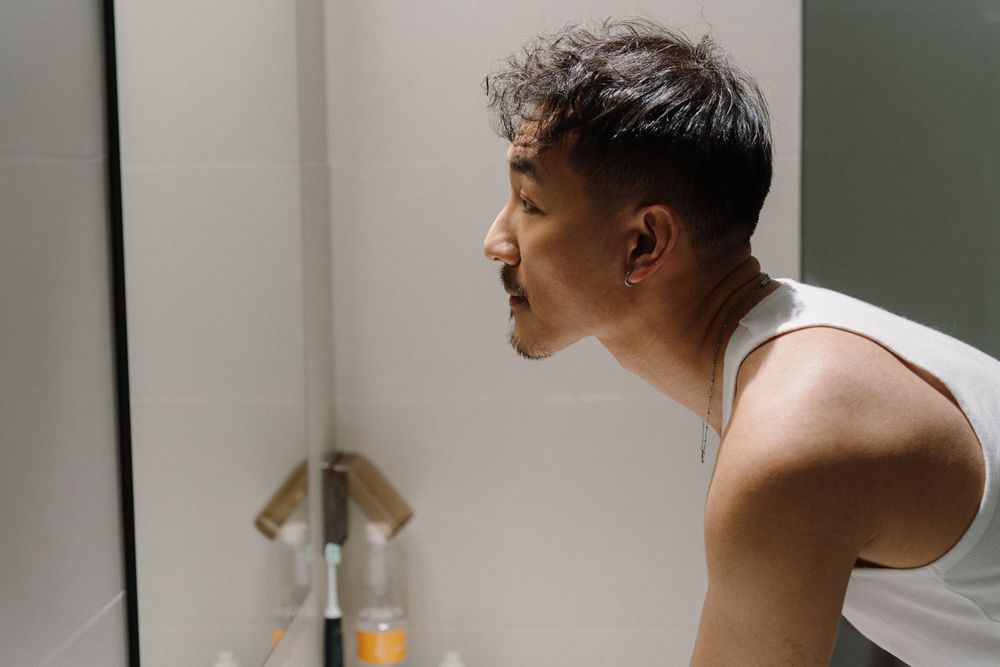 A side profile view of someone brushing their teeth in a bathroom.