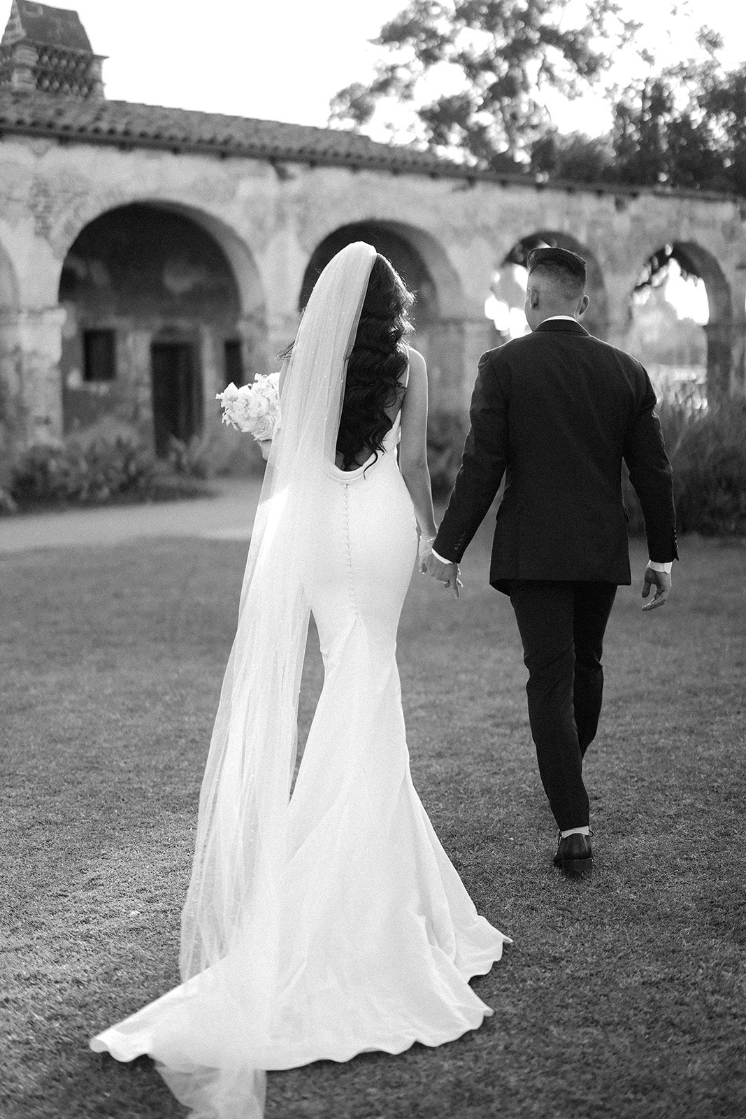 A sequence of black and white photos showing a bride in a flowing white dress and veil with groom walking on grass.