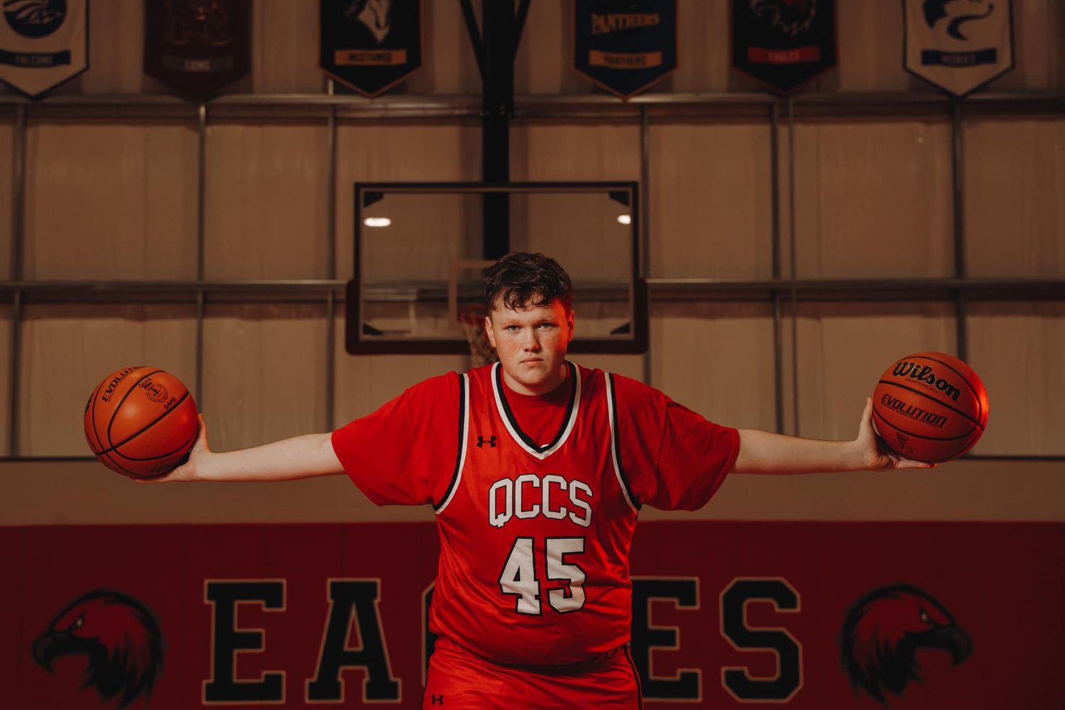 Basketball themed photoshoot in gymnasium with red jerseys and basketballs.